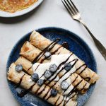 vegan crepes served with vegan cream, chocolate sauce and blueberries