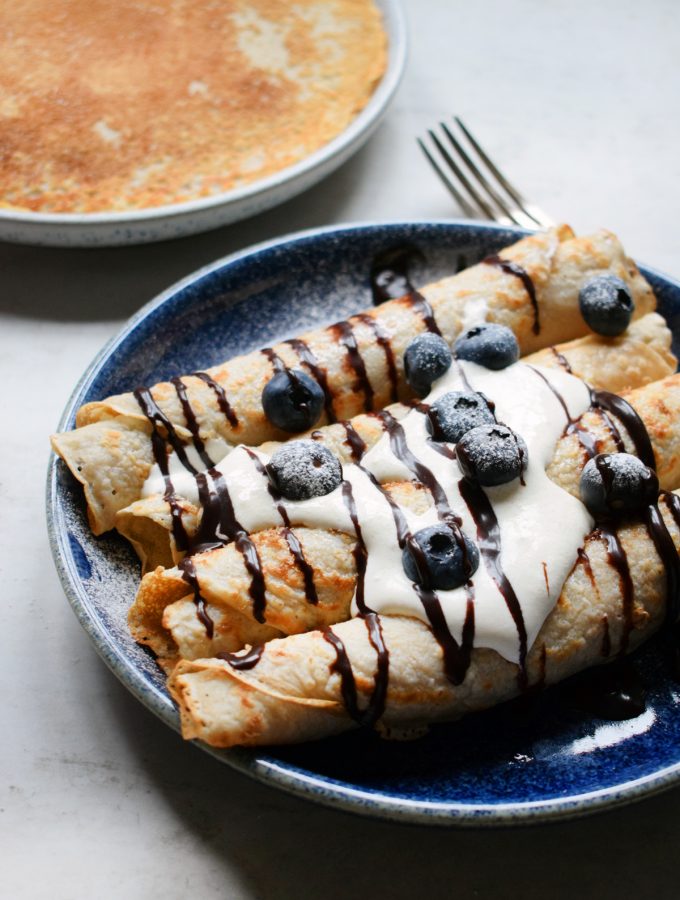 vegan crepes served with vegan cream, chocolate sauce and blueberries